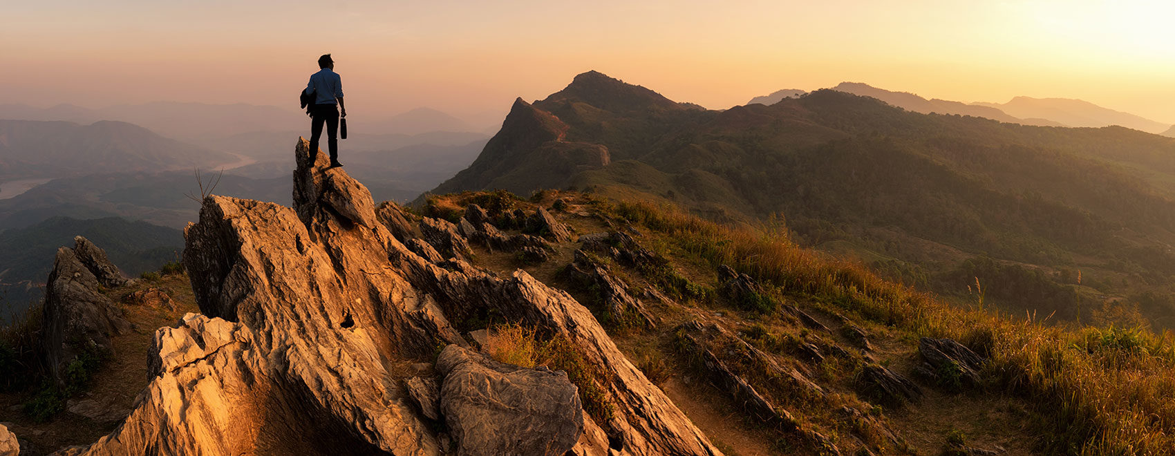 man on mountain looking at sunset