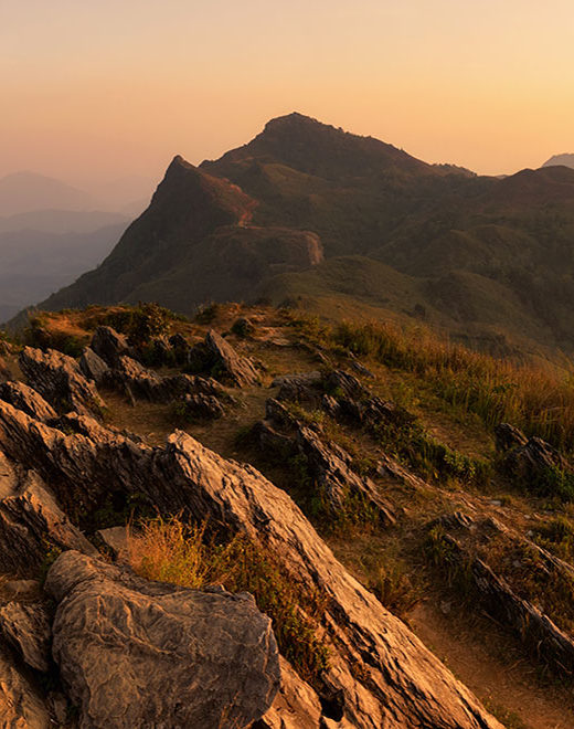 man on mountain looking at sunset