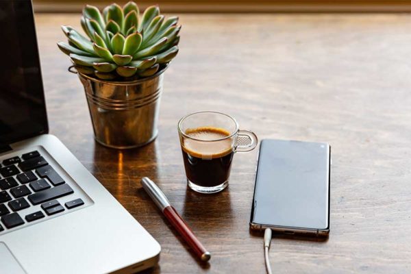 desk with laptop plant coffee cup and external hard drive